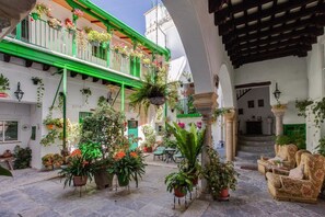 A courtyard with potted plants, outdoor seating, and a staircase leading to an upper level. - Apartamentos Jerez (Jerez de la Frontera)