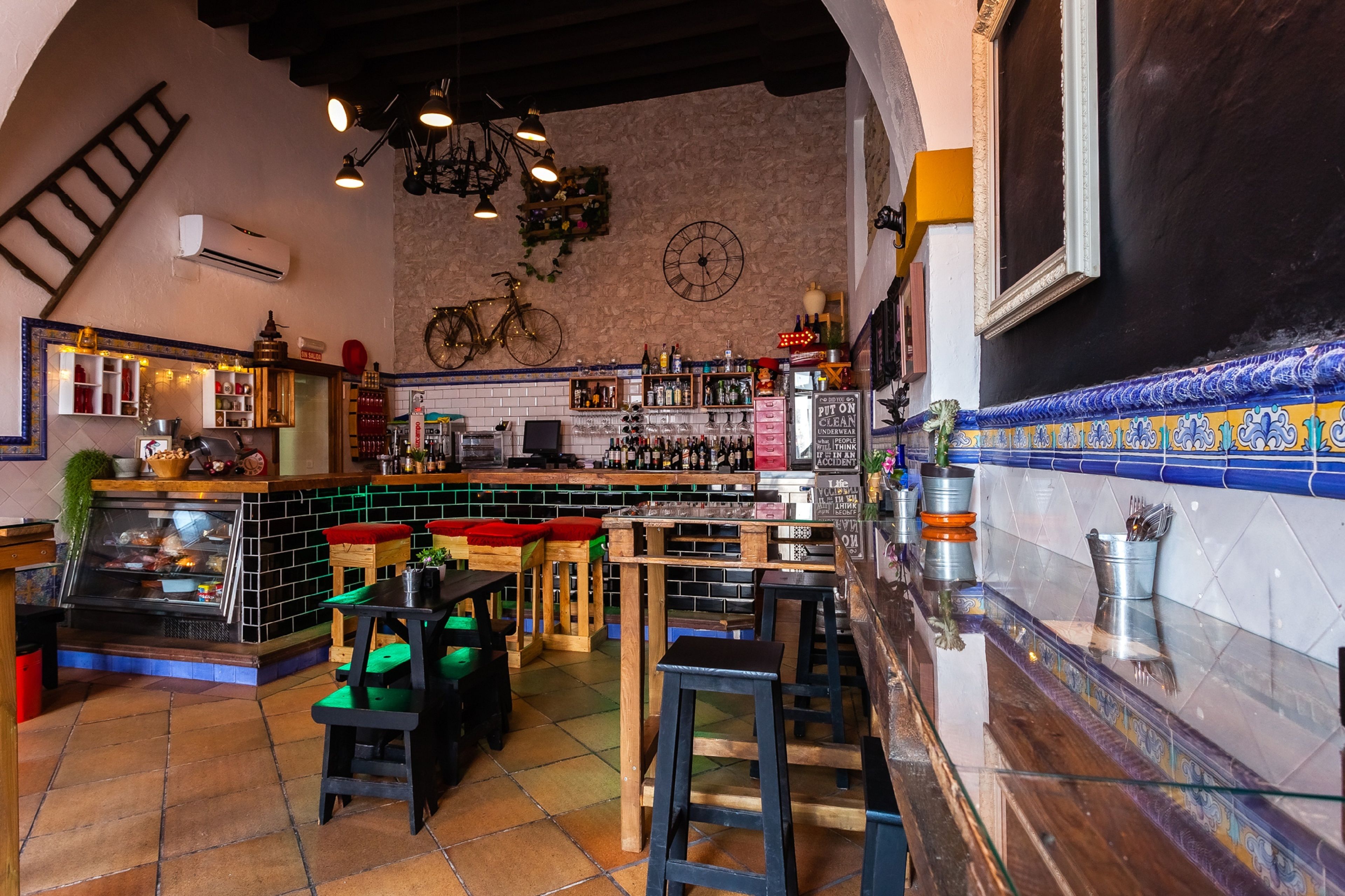 Angolo bar con sgabelli, un bancone e una sveglia appesa al muro.