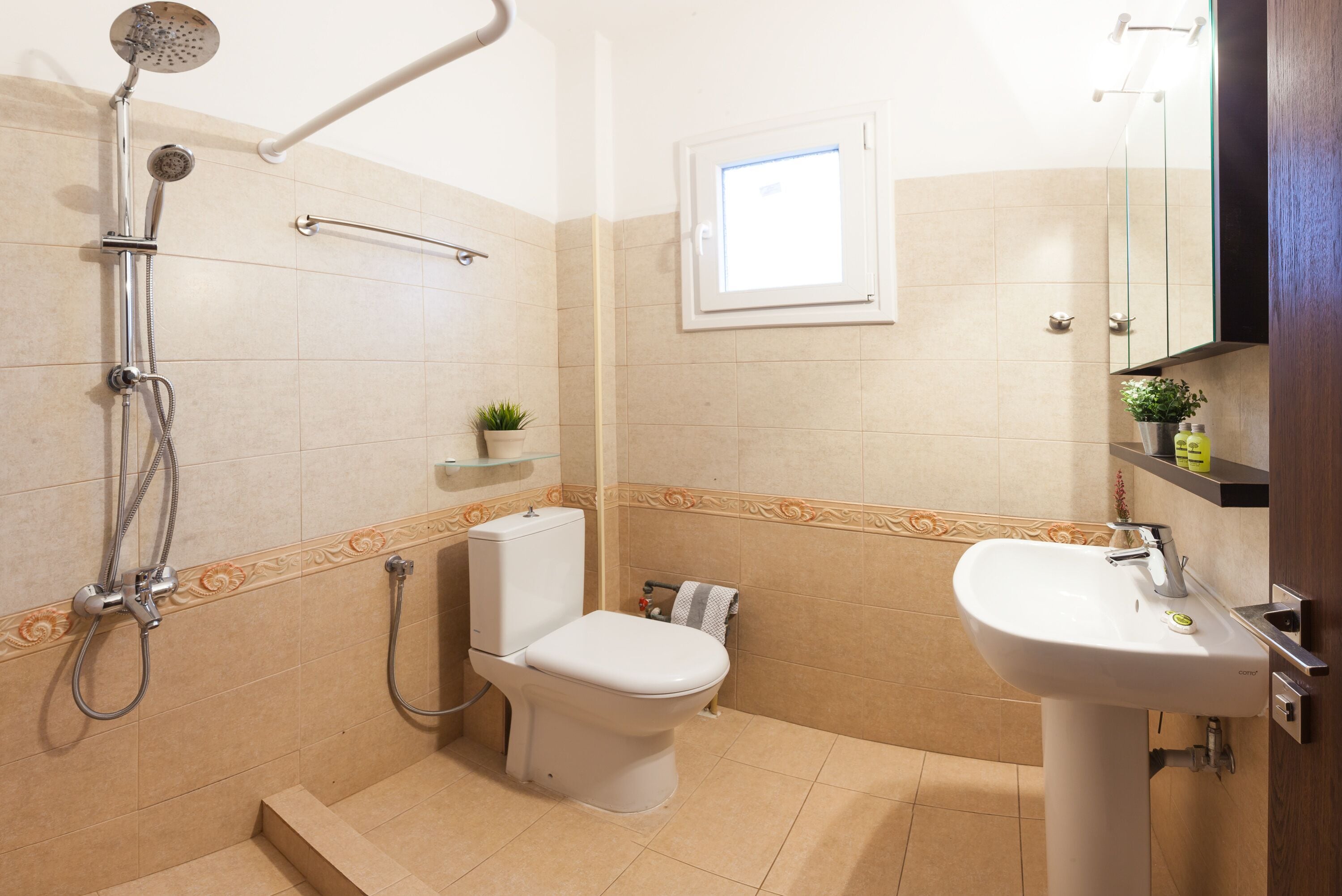 Un bagno con doccia, servizi igienici, lavandino e una piccola finestra.