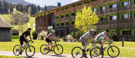 Un grupo de ciclistas en un camino con un edificio al fondo.