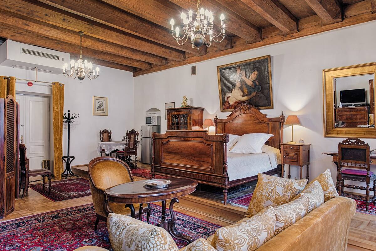 A traditional room with a wooden bed, a chandelier, a painting, and a television.