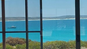 A view through a window with a clear blue sea and distant land.