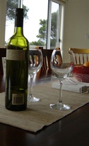 Una botella de vino y dos copas sobre una mesa con un mantel individual.