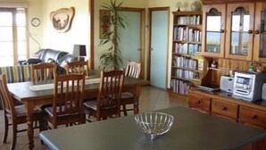 Un comedor con una mesa y sillas de madera, una estantería y una zona de cocina con microondas.