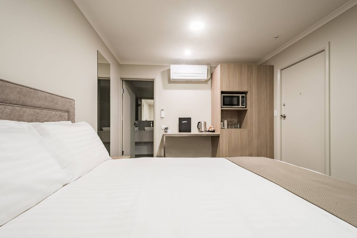 Habitación de hotel con cama, escritorio, microondas y armario.