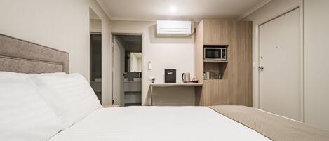 A hotel room with a bed, a desk, a microwave, and a wardrobe.