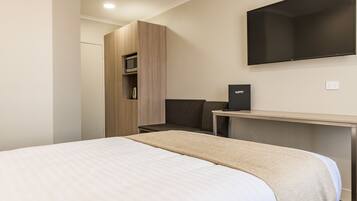 A modern hotel room with a bed, a desk, a flat-screen TV, and a wardrobe.