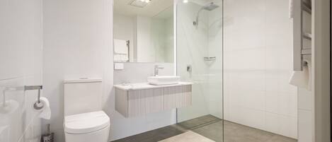 A modern bathroom with a toilet, sink, and glass shower enclosure.