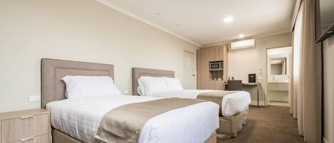 Habitación de hotel con dos camas, un escritorio, un espejo y un televisor.