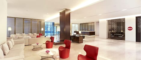 A spacious lobby with a reception desk, seating area, and a modern design.