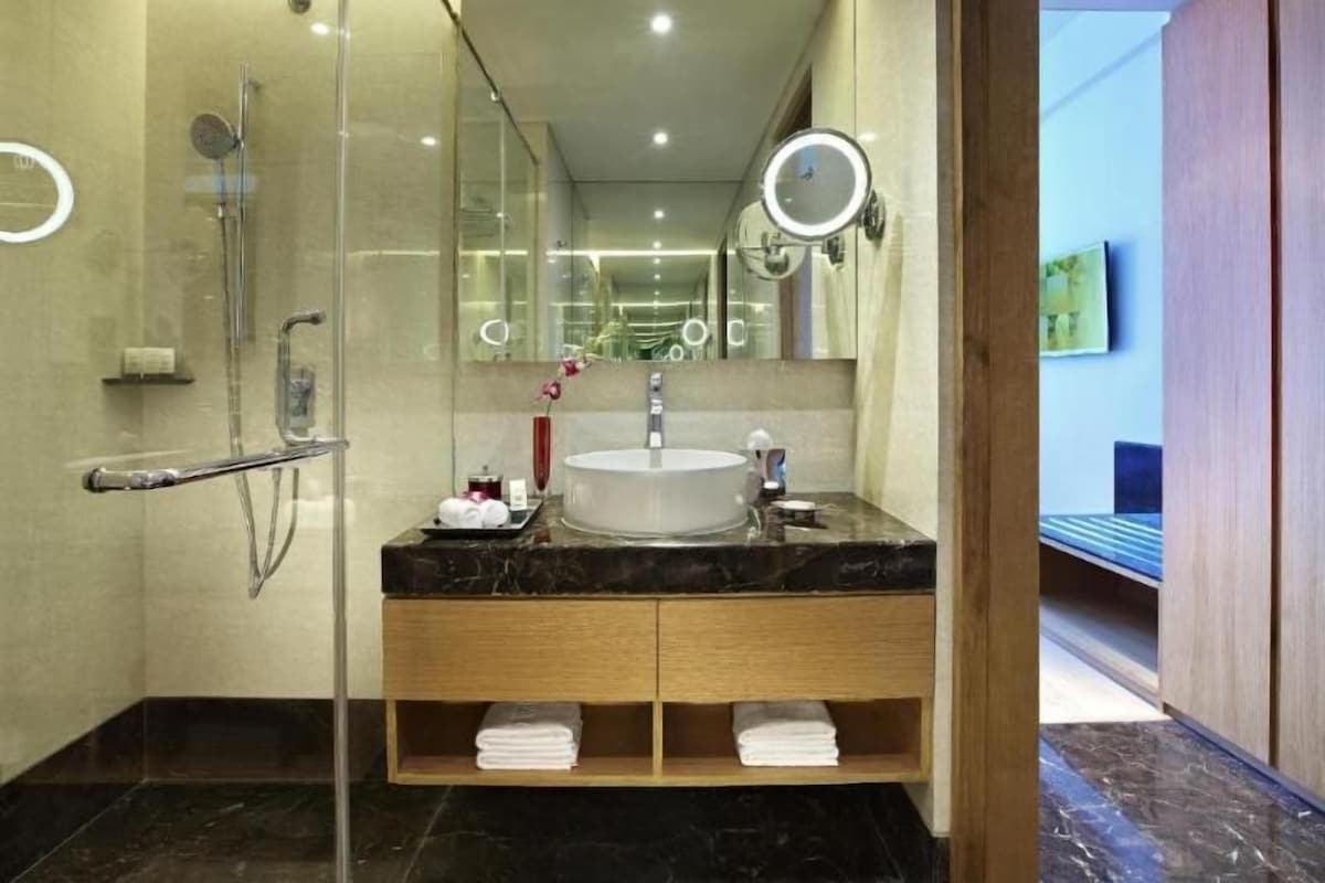 A modern bathroom with a glass-enclosed shower, a marble sink, and a wooden vanity.