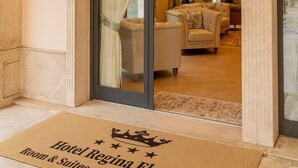 A hotel entrance with a doormat indicating "Hotel Regina Elena Room & Suites Private Parking."