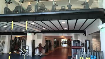 A gym with exercise equipment, a red and blue floor, and a ceiling with lights.