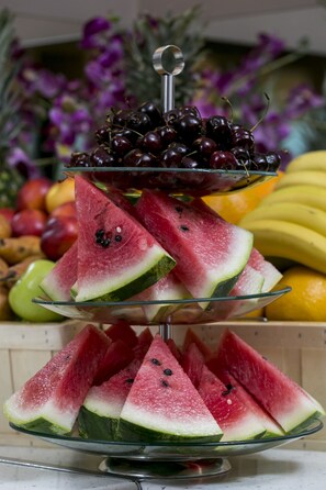 A three-tiered fruit stand with watermelon slices, cherries, and bananas.