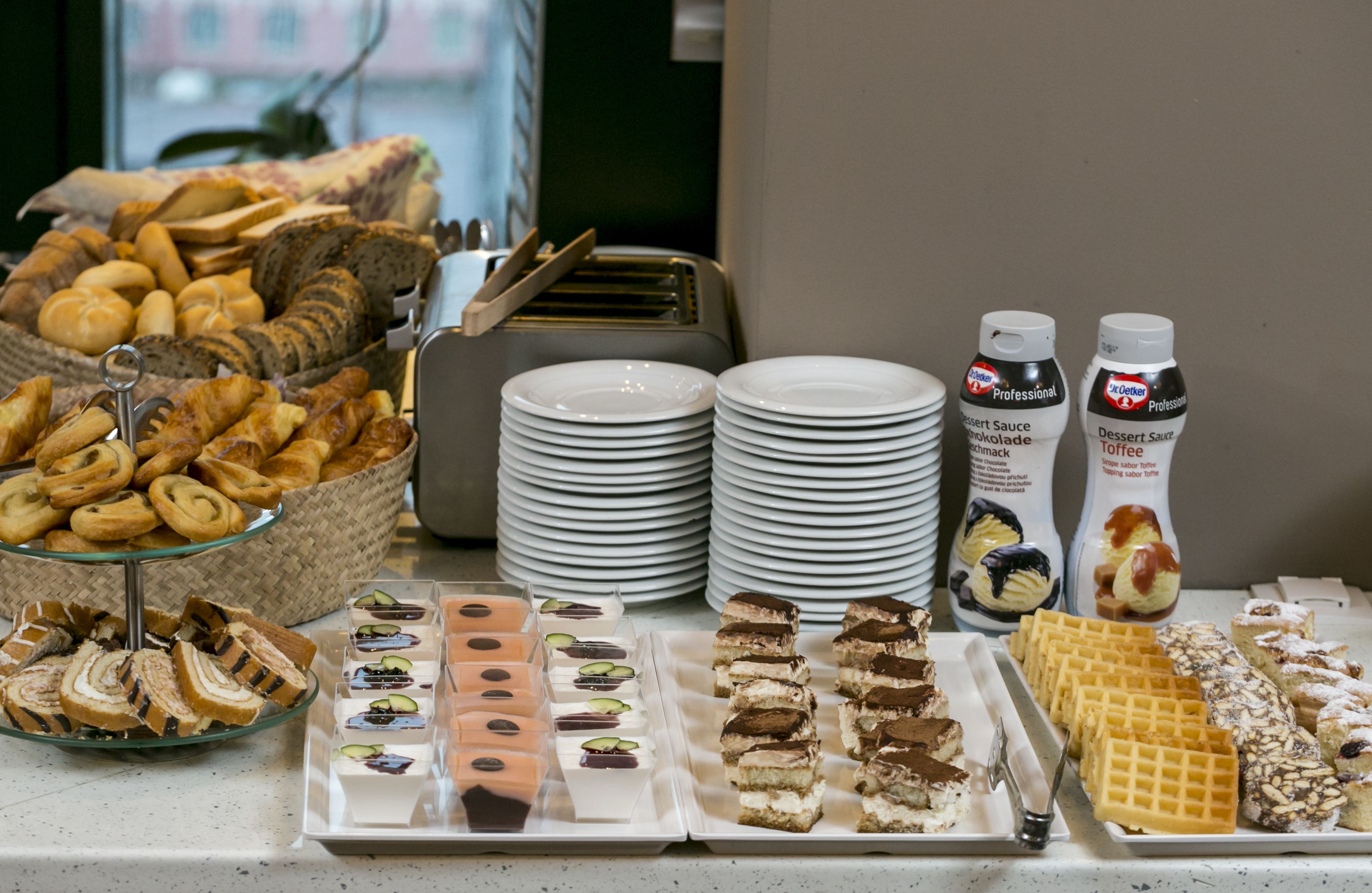 A buffet table with various pastries, desserts, and plates.