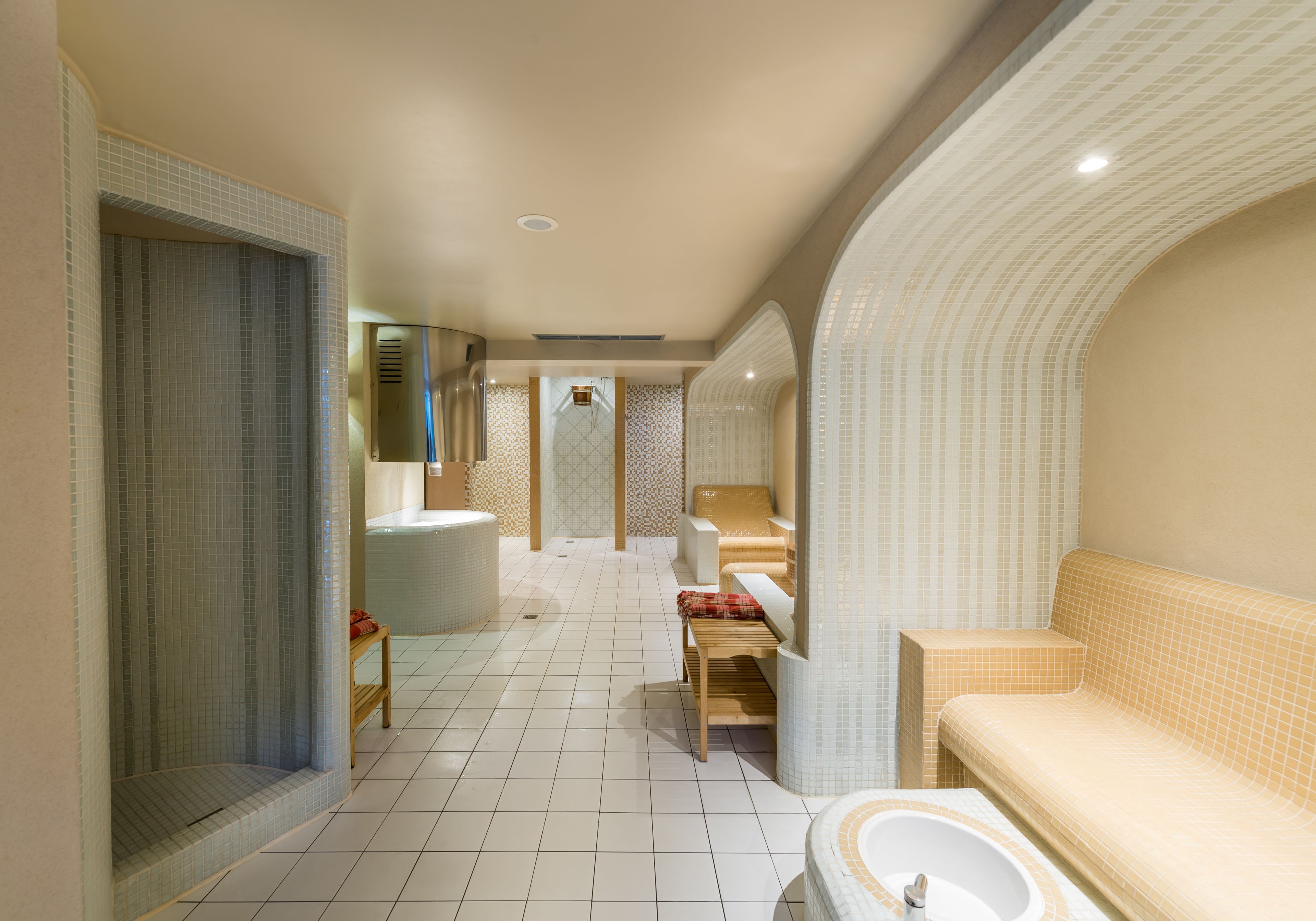 Un bagno moderno con una vasca, una doccia e un water. C'è una panca e uno specchio.