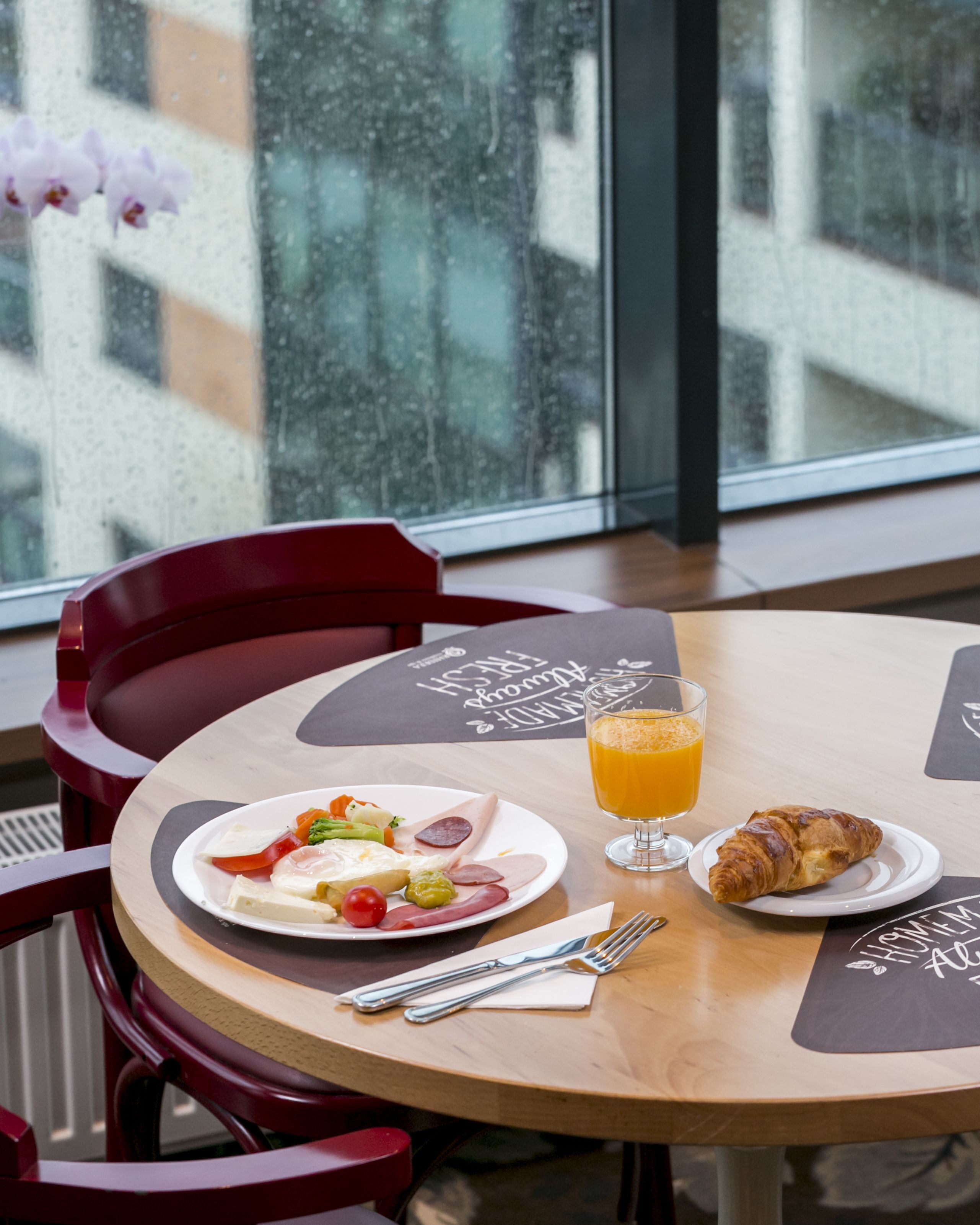 Ein Frühstückstisch mit Speisen, einem Orangensaftglas und einem Croissant.