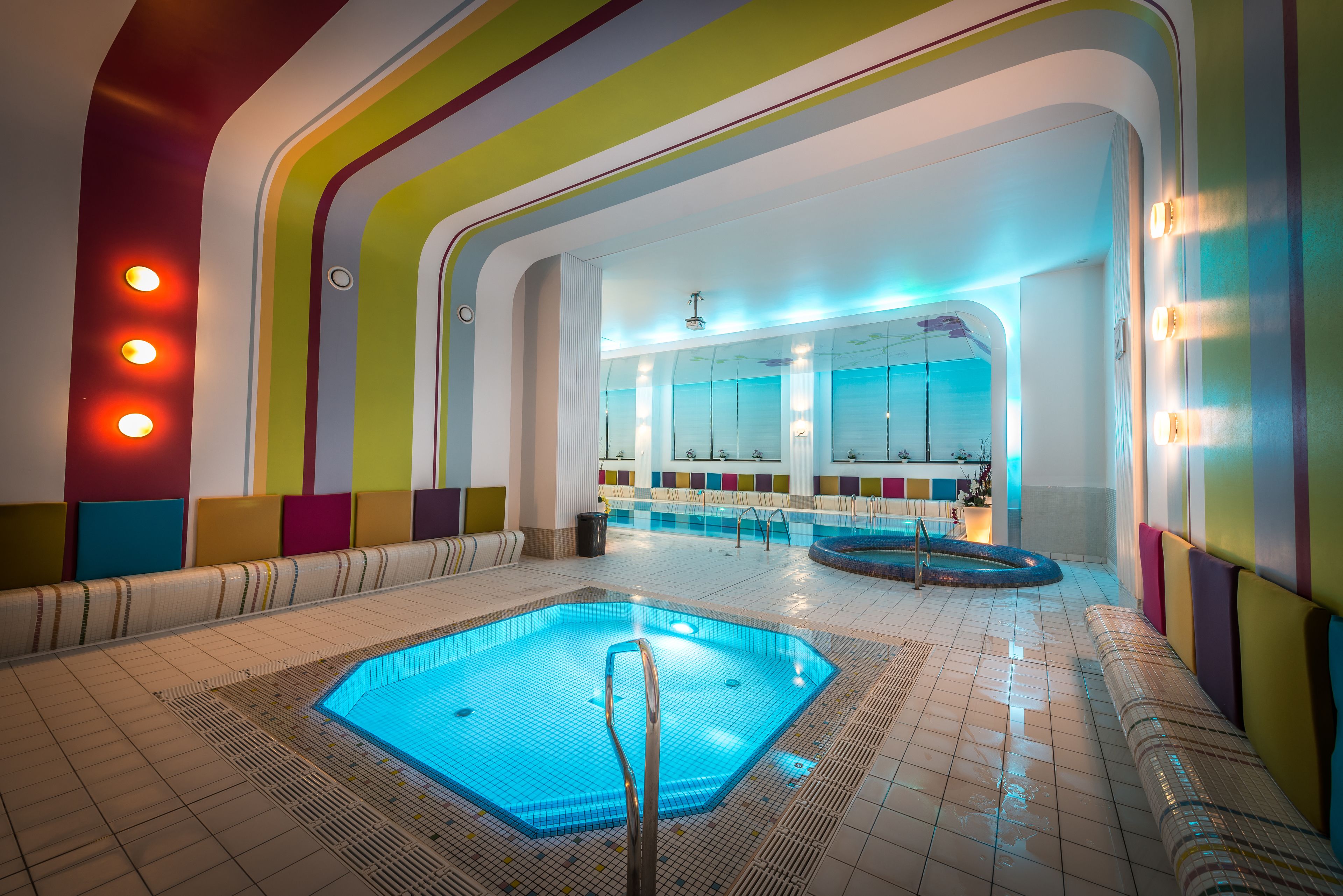 A swimming pool with a blue water feature, surrounded by colorful walls and seating areas.