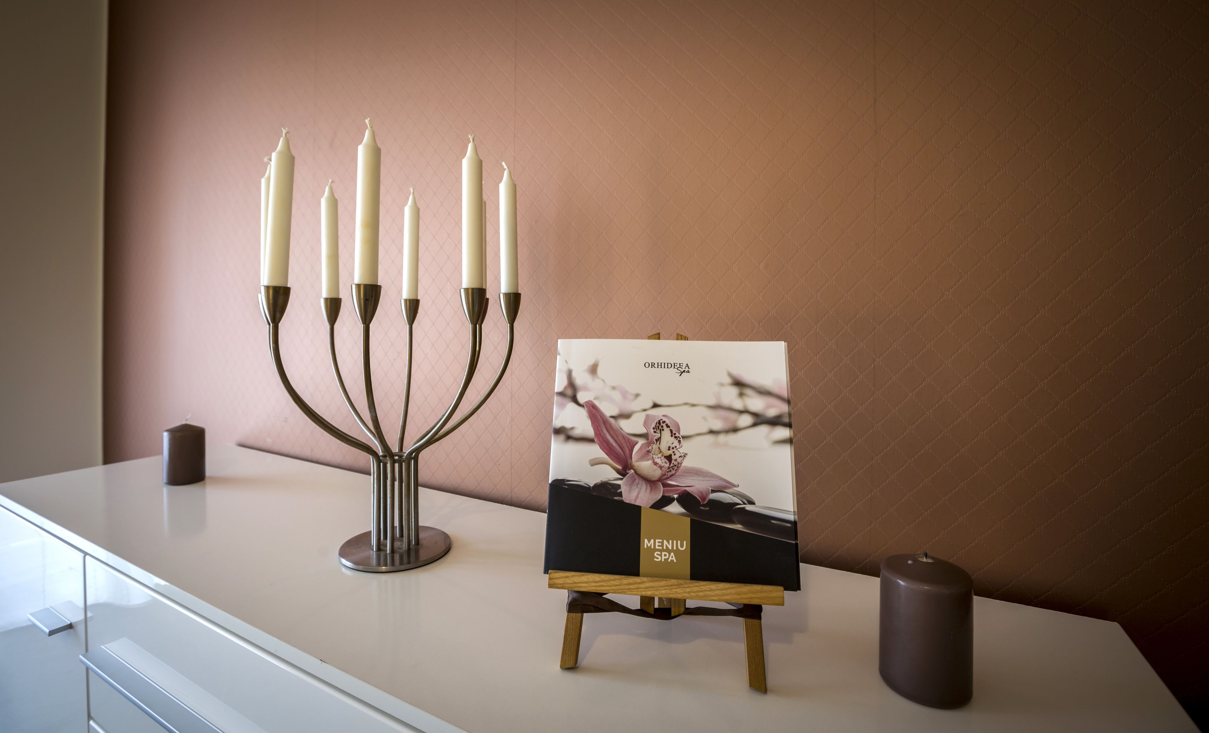 A menorah with seven candles, a framed picture of an orchid, and a candle on a white counter.