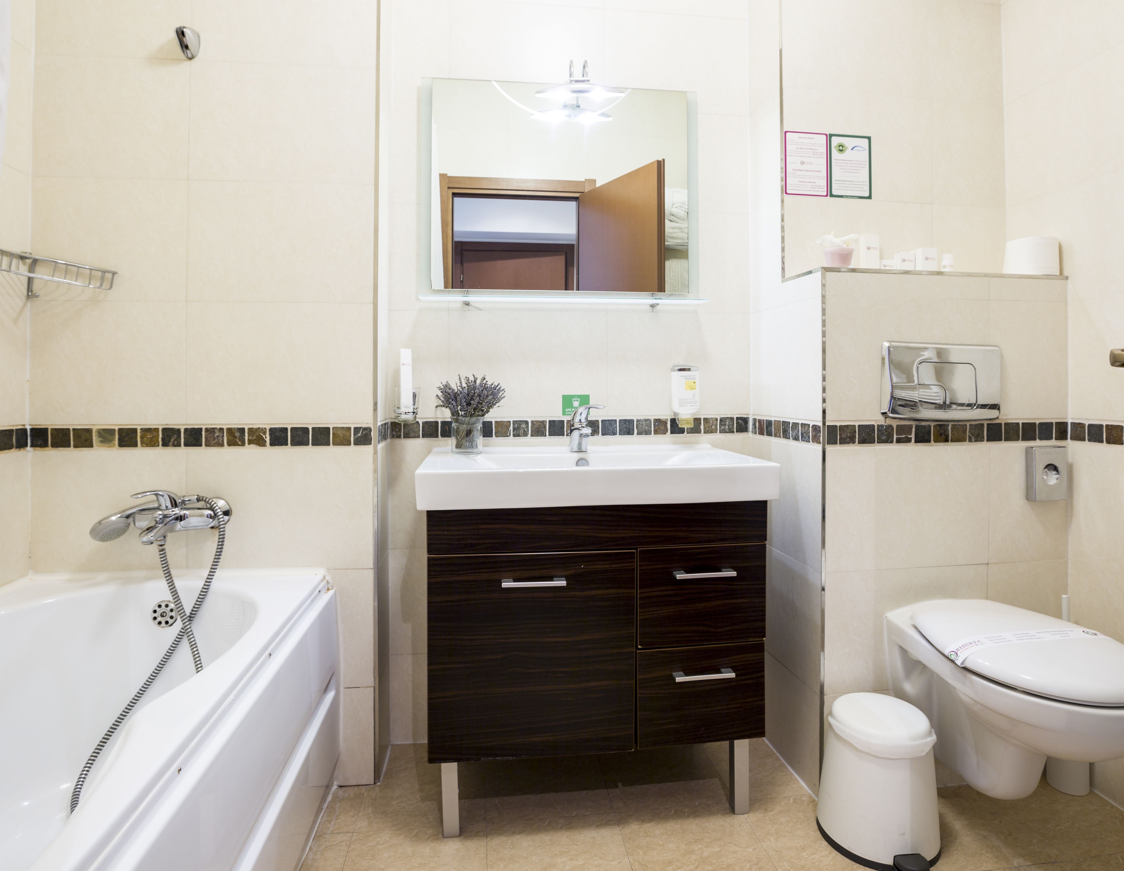 Ein Badezimmer mit einer Badewanne, einem Waschbecken, einer Toilette und einem Spiegel über dem Waschbecken.