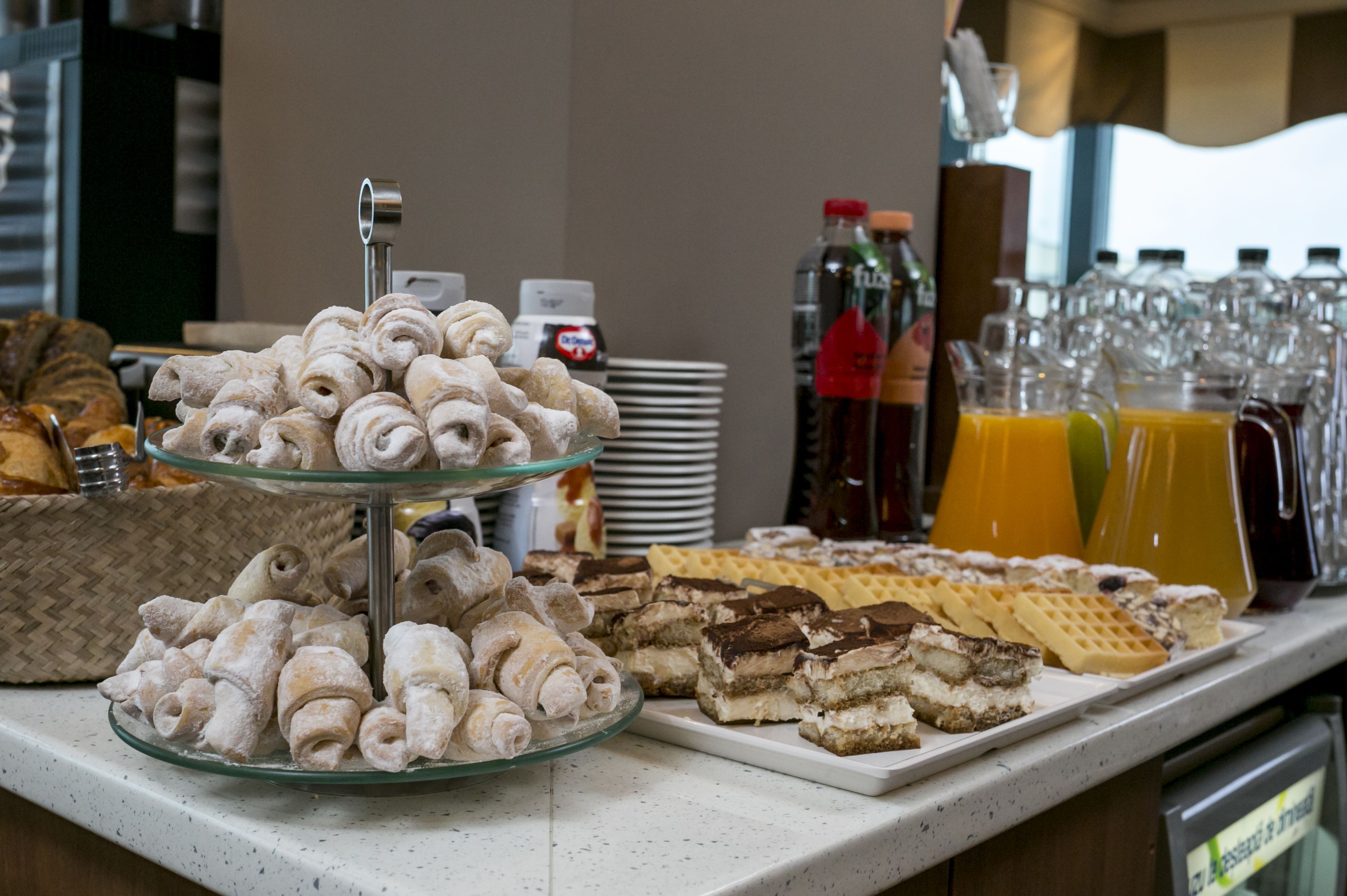 A buffet with various pastries, waffles, and a selection of beverages.