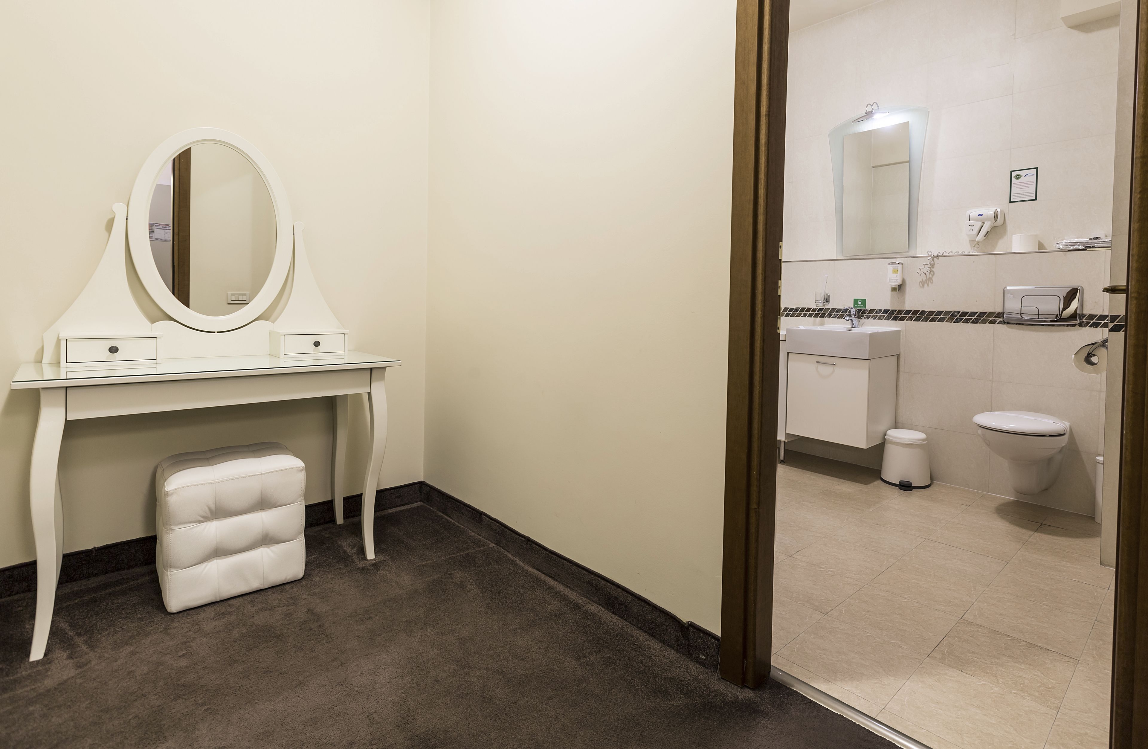 A hotel bathroom with a vanity, mirror, and toilet.