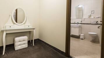 A hotel bathroom with a vanity, mirror, and toilet.