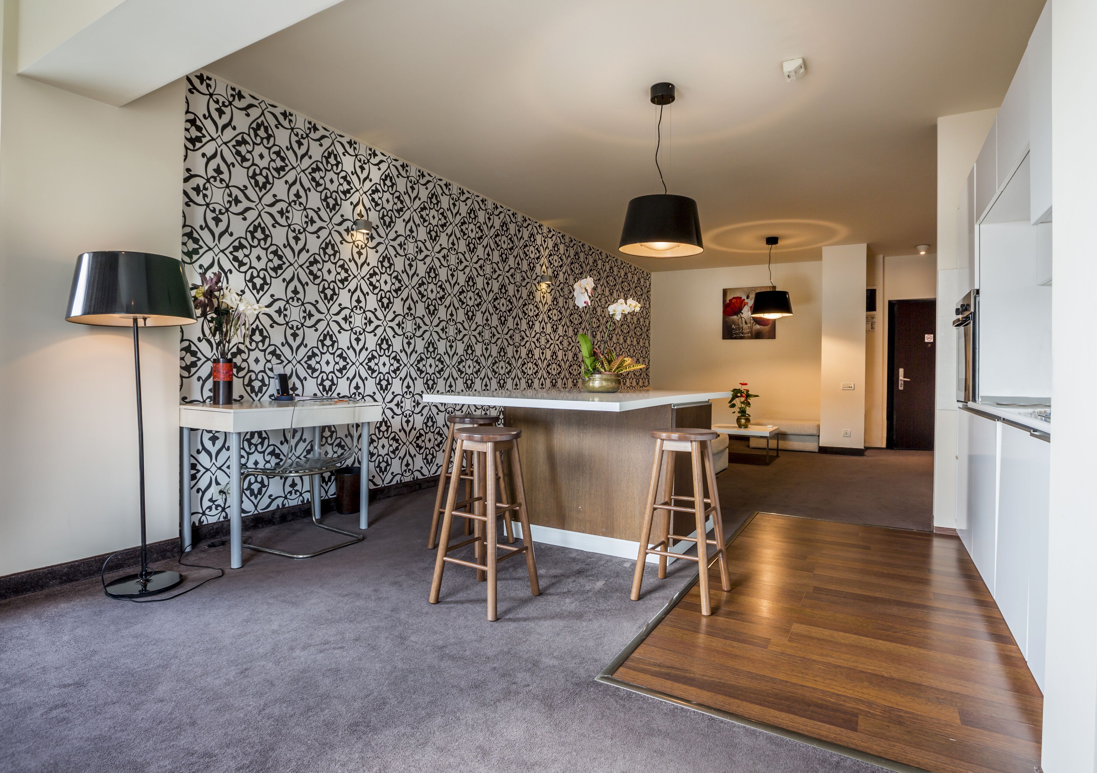 Eine moderne Küche mit einem gemusterten Spritzschutz, einer Bar mit Hockern und einem Holzboden.