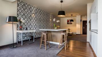 A modern kitchen with a patterned backsplash, a bar area with stools, and a wooden floor.