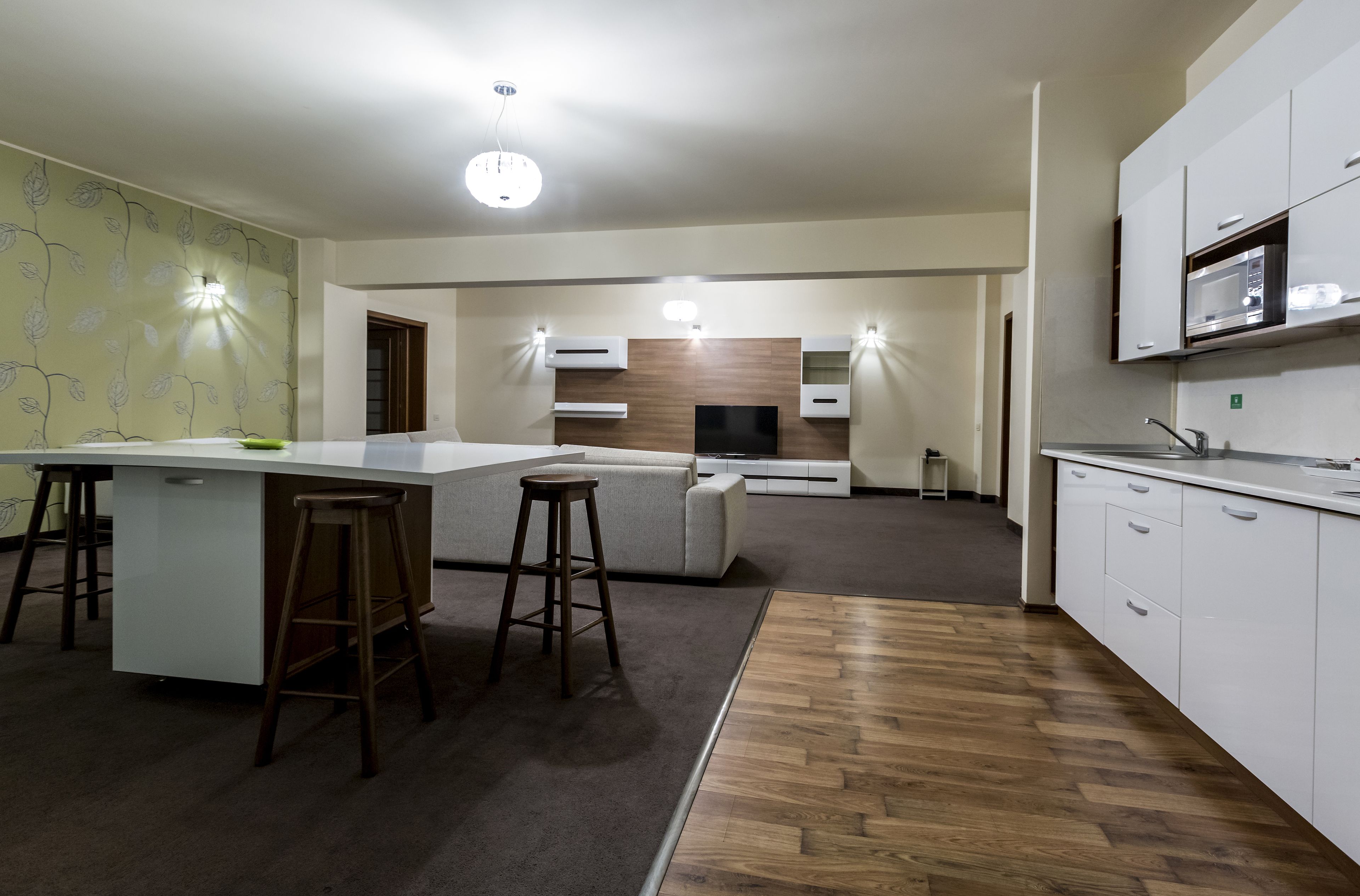 Uma cozinha moderna com uma ilha central, banquetas, micro-ondas e forno embutido.