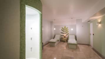 Un baño tipo spa con pared curva, un lavamanos, dos sillas, una planta decorativa y suelo de baldosas.