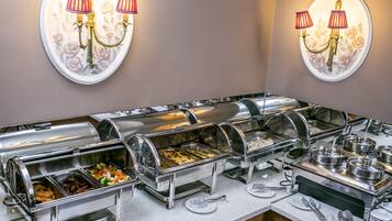 Un espace buffet comprenant plusieurs stations de service où les clients peuvent se servir eux-mêmes, avec différents plats présentés sur des plateaux et une variété d’ustensiles à disposition sur le comptoir.