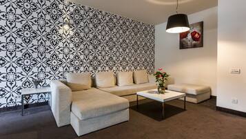 A modern living room with a patterned wallpaper, a sectional sofa, a coffee table, and a pendant light.