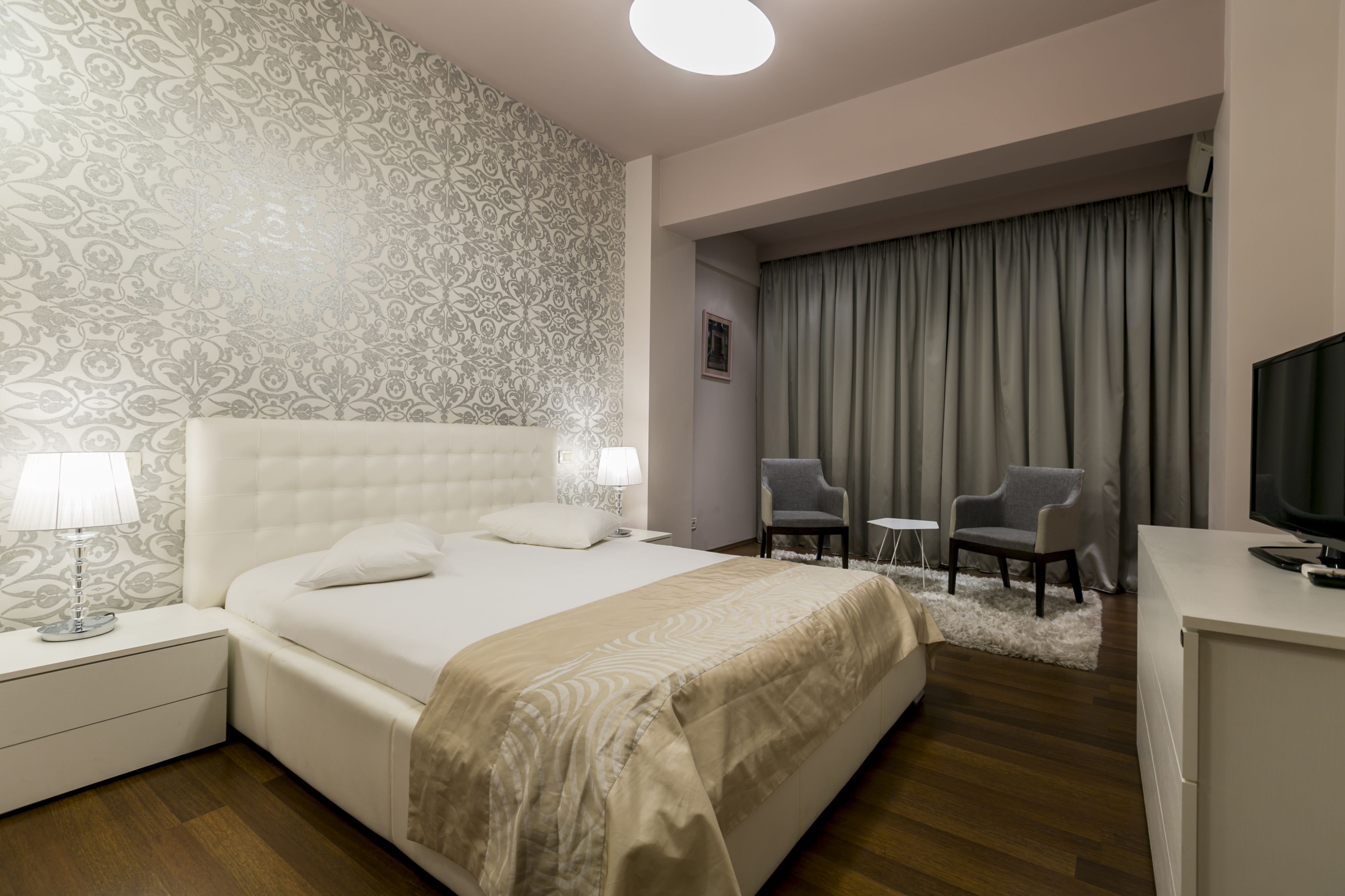 Una habitación de hotel con una cama grande, dos sillas, un escritorio y un televisor.