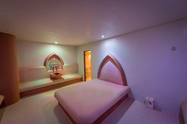 Una habitación de hotel moderna con una cama grande, un área de descanso con un cuenco decorativo y una ventana pequeña.