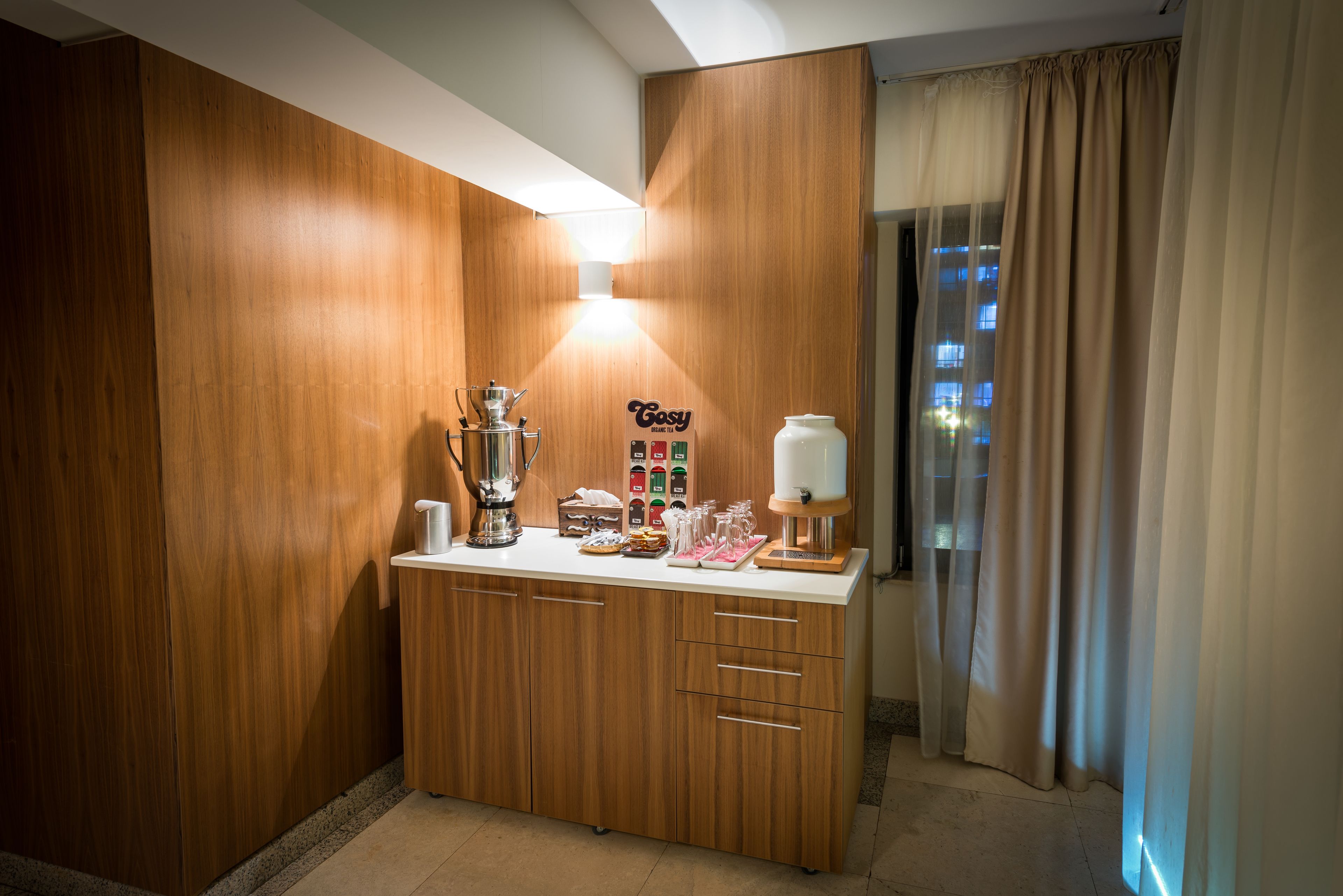 A kitchenette with wooden cabinets, a coffee machine, a tea kettle, and a small refrigerator.