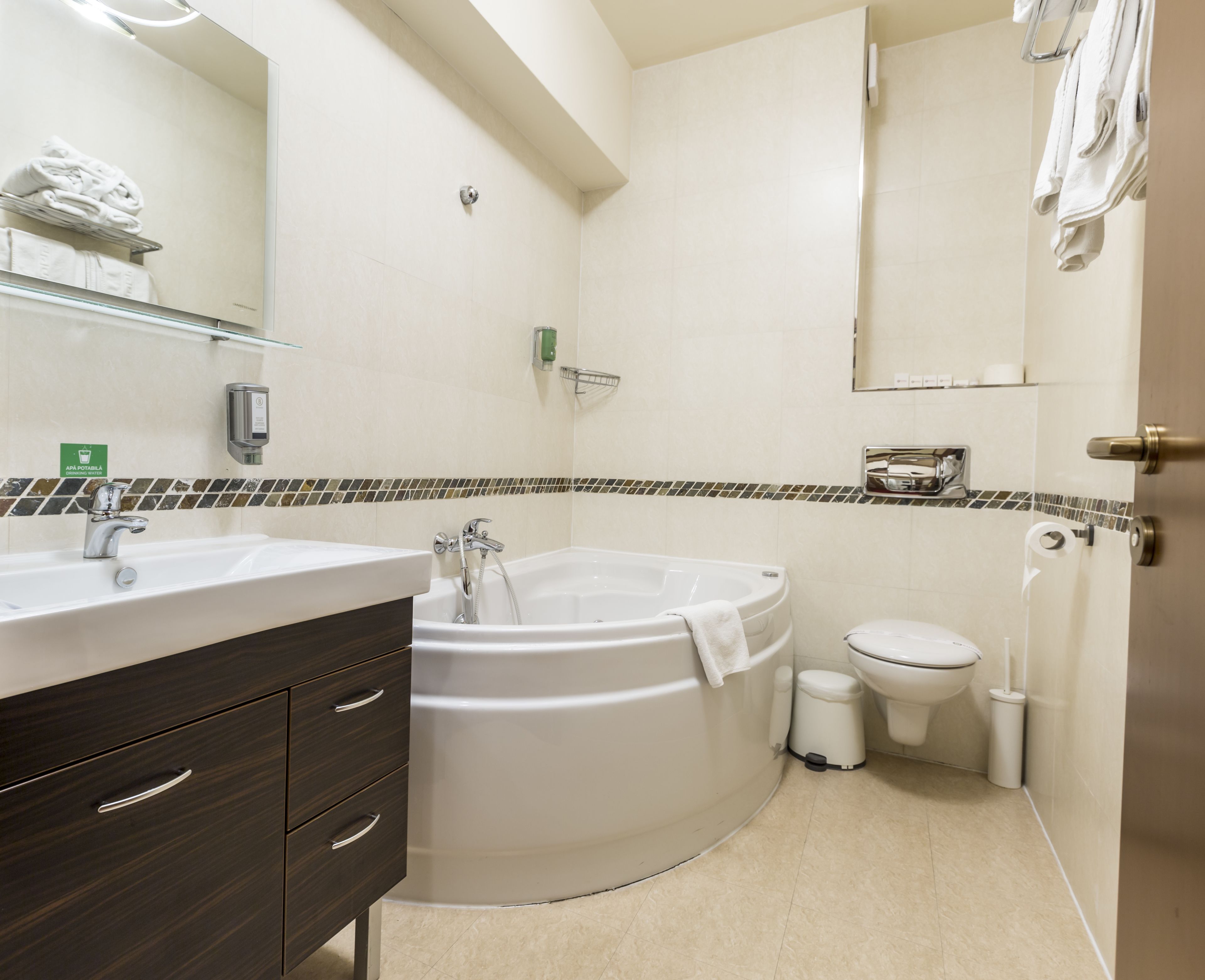 Un baño moderno con una bañera grande, un lavabo, un inodoro y un espejo.