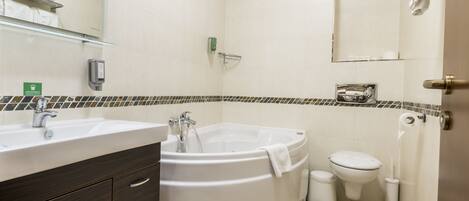 Un baño moderno con una bañera grande, un lavabo, un inodoro y un espejo.