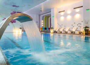 An indoor swimming pool with a waterfall feature, lounge chairs, and a colorful wall design. - Orhideea Residence & Spa (Bucharest)