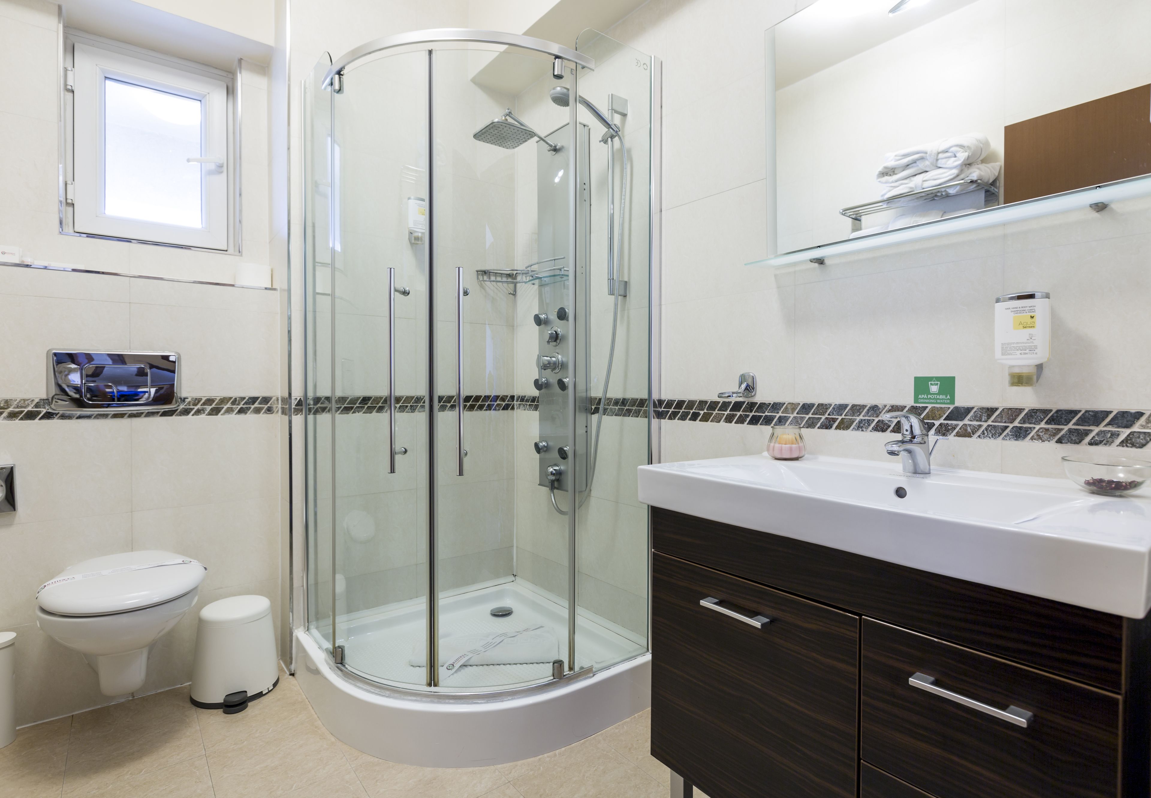 Un baño moderno con ducha de vidrio, lavamanos blanco y tocador de madera oscura.