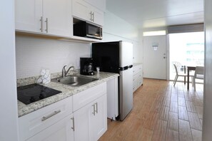 A kitchen with white cabinets, a stainless steel sink, a microwave, a coffee maker, and a refrigerator. - Paradise Oceanfront Resort (Wildwood Crest)