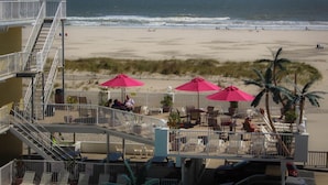 A beachside view with a restaurant patio, outdoor seating, and a view of the ocean. - Paradise Oceanfront Resort (Wildwood Crest)