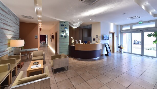 A hotel reception area with a reception desk, seating area, and a large window with a view of the outside.