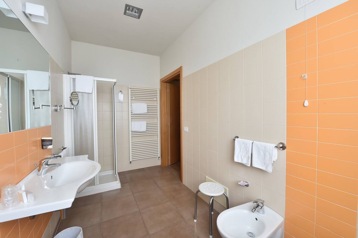 A modern bathroom with two sinks, a shower, and a toilet.