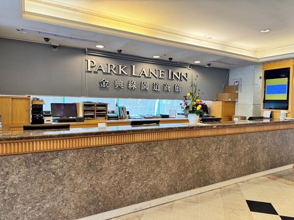 Una mesa de recepción con un cartel que dice "Park Lane Inn" y un arreglo floral.