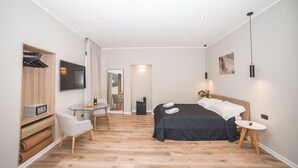 A modern hotel room with a bed, a TV, a desk, and a chair. - Rome King Suite (Rome)