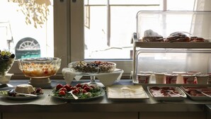 A buffet table with various food items including a salad, fruit, and desserts. - Rome King Suite (Rome)