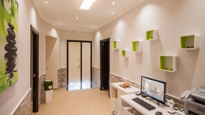 A modern hotel lobby with a reception desk, computer, printer, and green storage shelves. - Rome King Suite (Rome)