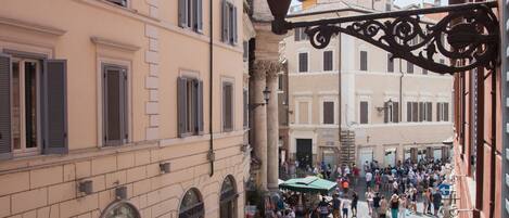 A cobblestone street with pedestrians, historic buildings, and a street lamp.