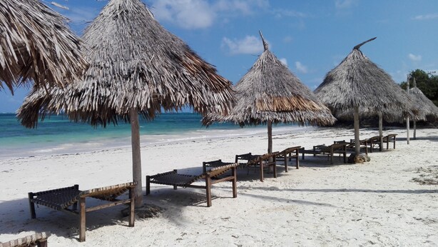 A beach with thatched umbrellas and wooden benches. - Flamingo Villas Resort (Malindi)